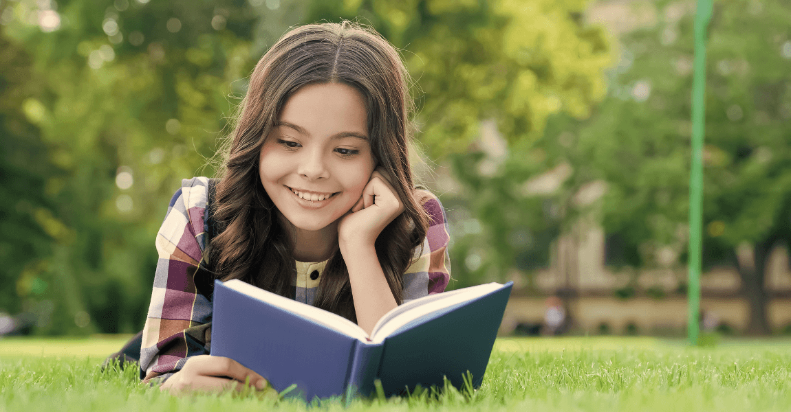 Meisje leest buiten in een boek als oefening voor DMT-toetsen en technisch lezen op de basisschool