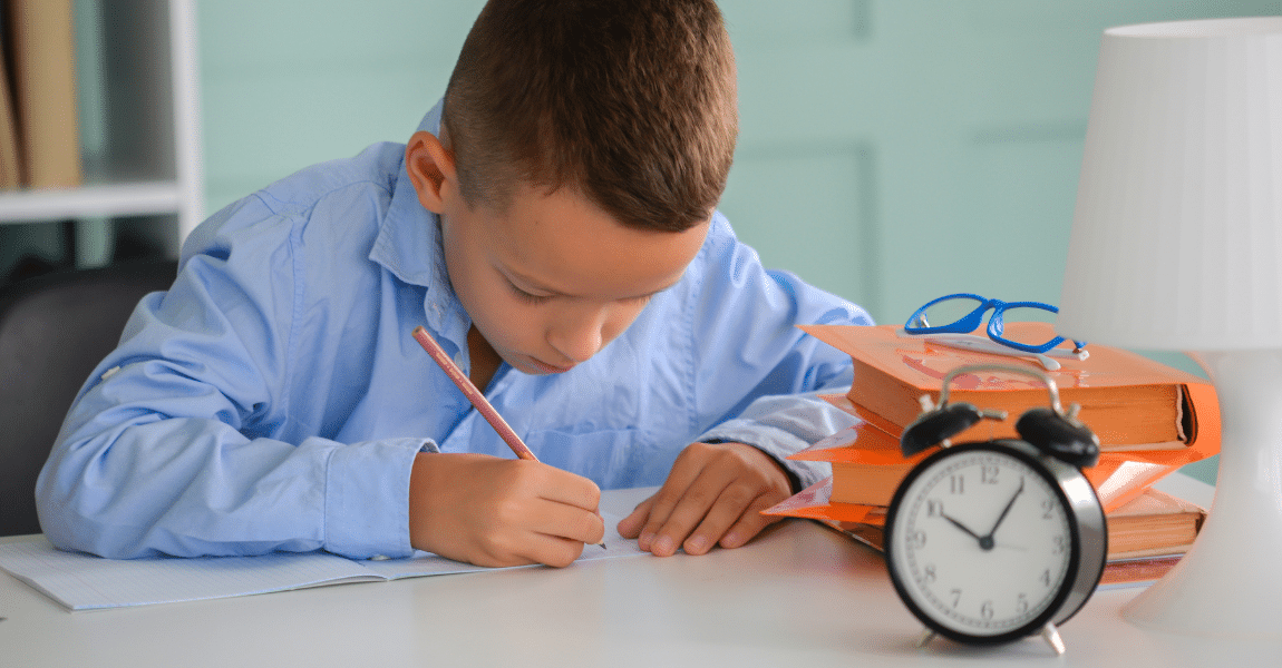 Kind oefent tempotoetsen aan tafel met schrift, boeken en wekker voor zich