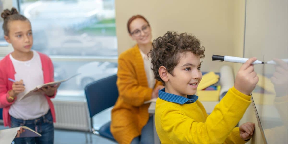 Een leerling oefent met de bedrijvende en lijdende vorm op een whiteboard.