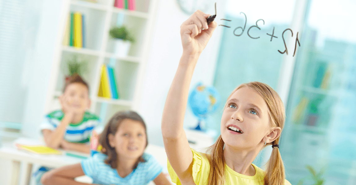 Meisje oefent rekenen groep 6 in de klas terwijl ze een rekensom op het bord schrijft