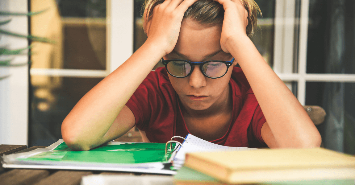 Kind met schoolwerk aan tafel dat zich zorgen maakt over blijven zitten op de basisschool