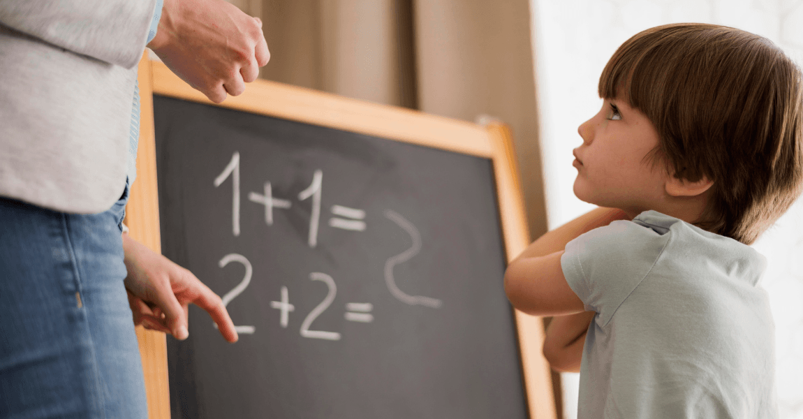 Kind oefent thuis met eenvoudige rekenspelletjes voor groep 1 en 2 op een schoolbord samen met een ouder