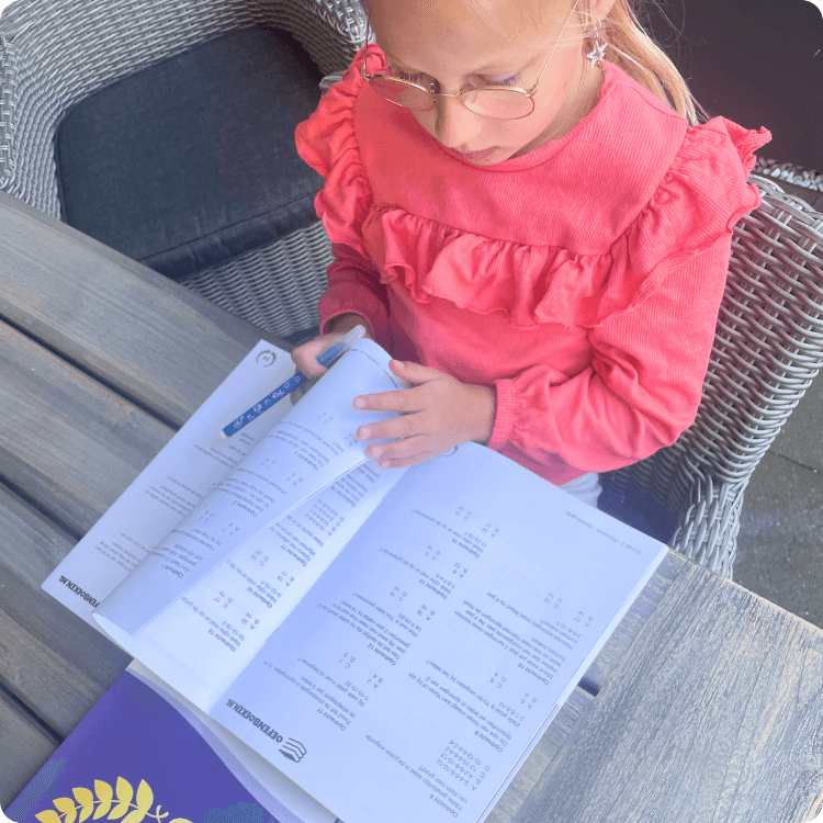 Kind uit groep 4 oefent zelfstandig met werkbladen en een oefenboek voor rekenen en spelling