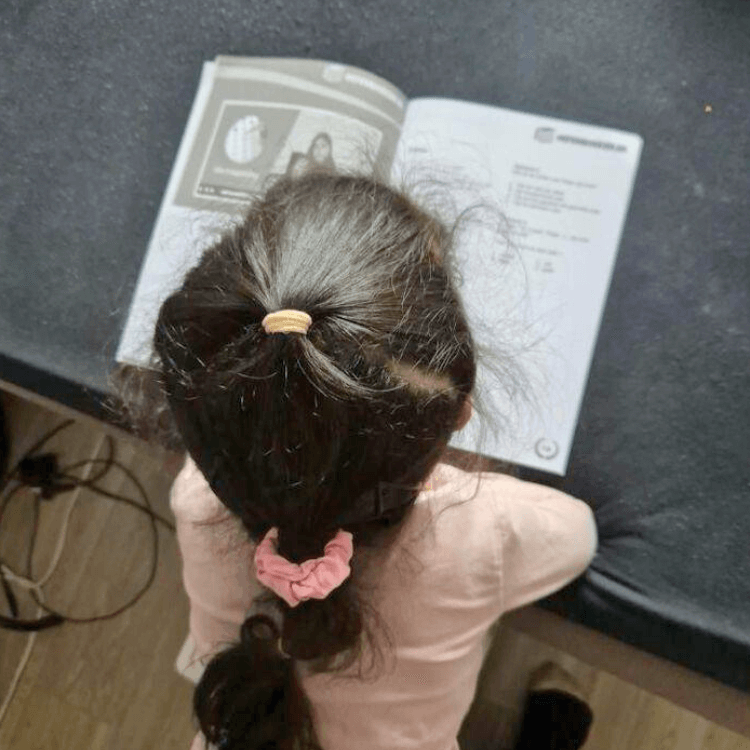 Kind uit groep 5 oefent rekenen en taal met een oefenboek dat aansluit bij de leerstof van school