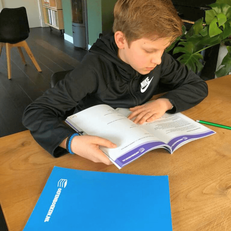 Leerling uit groep 7 werkt zelfstandig in een oefenboek met opdrachten voor rekenen lezen en spelling
