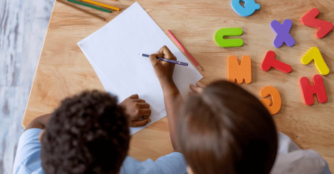 Kind oefent aan tafel met letters en leert het verschil tussen klinkers en medeklinkers herkennen