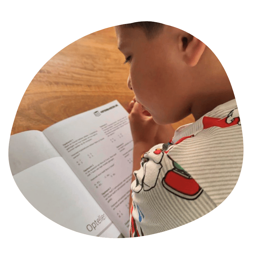 Kind oefent thuis met een oefenboek rekenen groep 7 aan tafel.