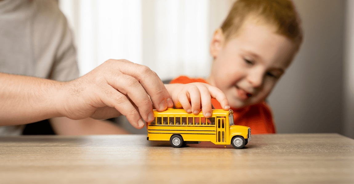 Kind oefent bussommen groep 3 met een speelgoedbus samen met een ouder aan tafel
