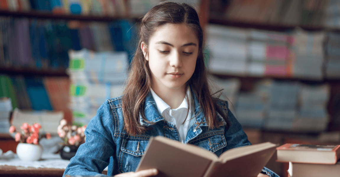Meisje uit groep 7 leest geconcentreerd een boek als voorbereiding op dictee en spelling oefenen