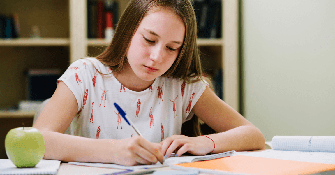 Meisje oefent thuis met dictee groep 8 en werkt aan spelling en moeilijke woorden aan tafel
