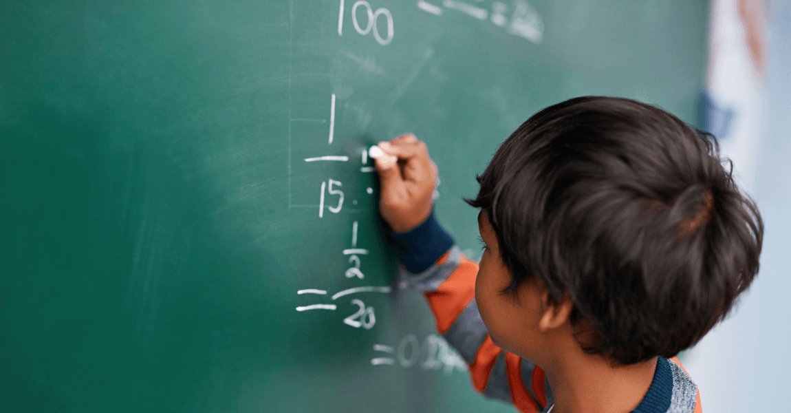 Kind rekent met breuken op het schoolbord tijdens uitleg over het kleinste gemene veelvoud.