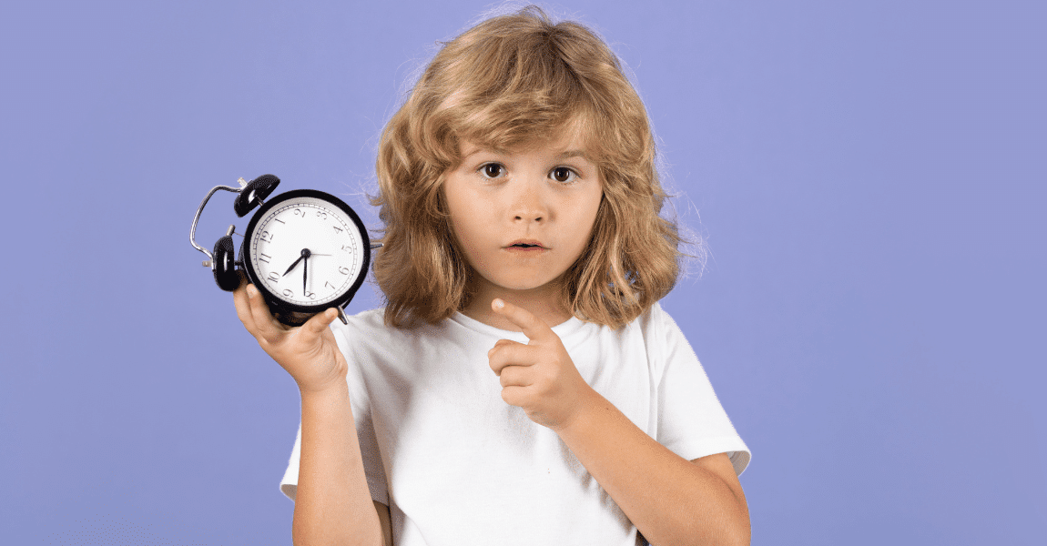 Kind oefent klokkijken in groep 4 met een analoge wekker en wijst naar de tijd