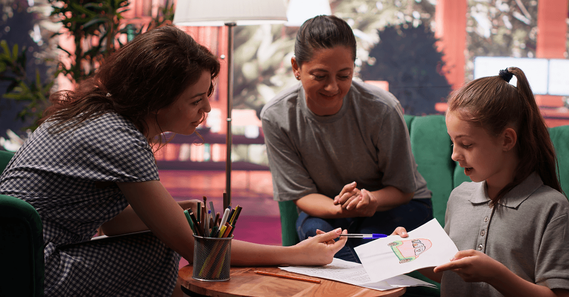 Leerkracht en ouder voeren een rapportgesprek op de basisschool terwijl een kind werk laat zien aan tafel