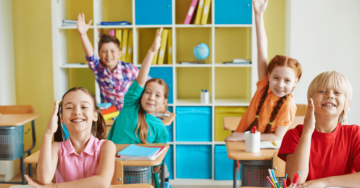 Kinderen in een klaslokaal steken hun hand op tijdens een les over spellingsregels op de basisschool