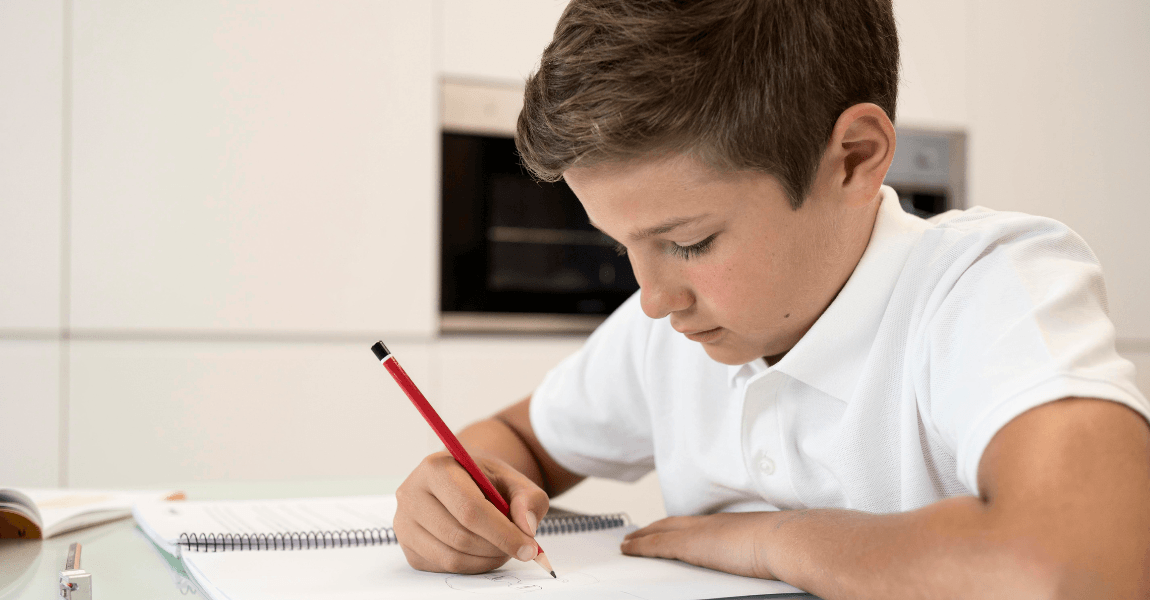 Jongen maakt rekensommen aan tafel en oefent thuis met staartdeling uitleg voor de basisschool