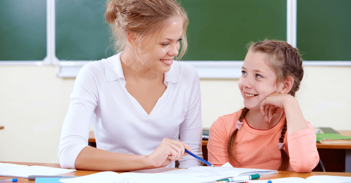 Leerkracht helpt basisschoolkind met spelling oefenen rond aan elkaar schrijven of los schrijven.