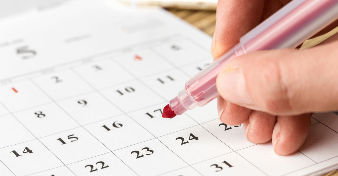 Kind markeert een datum op een kalender om de afkorting van maanden en datums te oefenen.