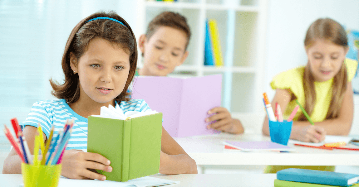 Kind leest een boek in de klas en oefent met alle spreekwoorden en gezegden op een rij voor taalbegrip.