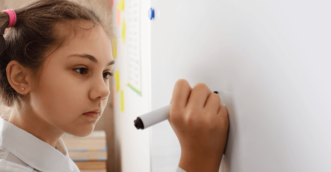 Kind oefent breuken optellen en aftrekken op een whiteboard tijdens rekenles op de basisschool.