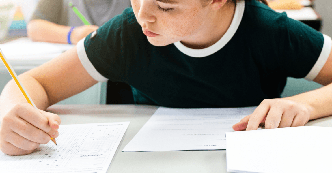 Kind op de basisschool maakt een toets terwijl ouders uitleg zoeken over Cito scores en toetsresultaten.