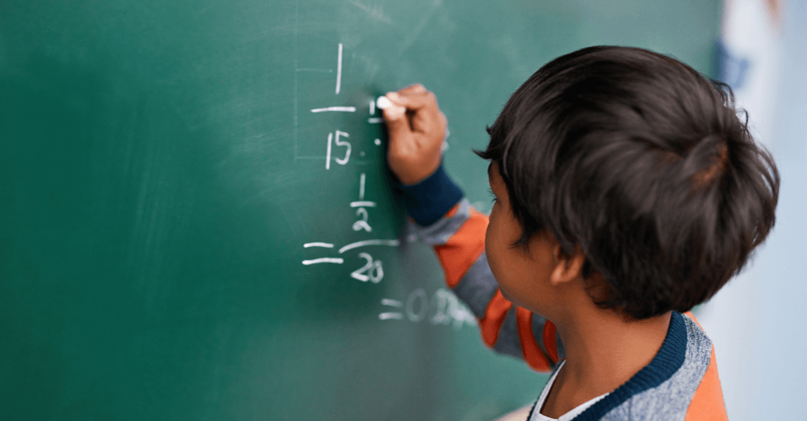Kind oefent delen oefeningen op het schoolbord om deelsommen beter te leren begrijpen.