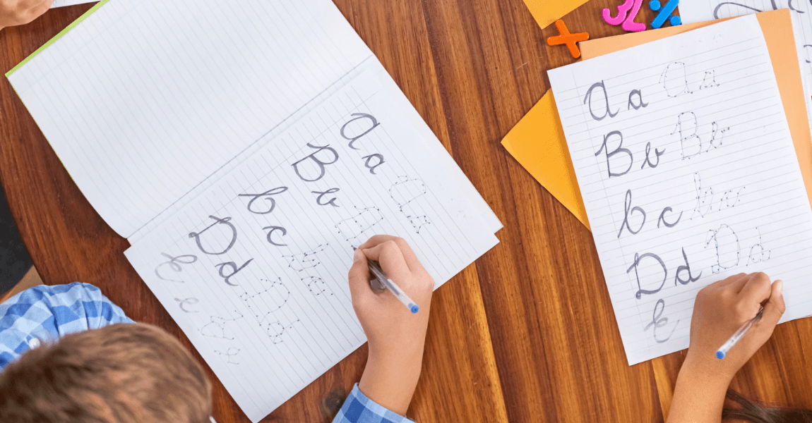 Kinderen oefenen hoofdletters schrijven op een werkblad voor taal en spelling op de basisschool.