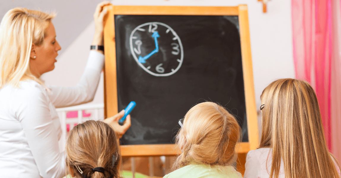 Kinderen oefenen met klokken zonder wijzers terwijl een leerkracht een analoge klok uitlegt op het schoolbord.