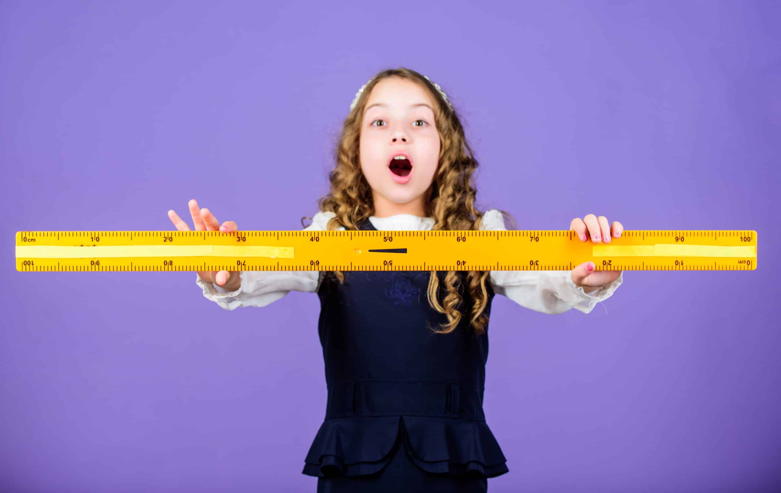 Kind oefent met een grote liniaal om meters, cm en mm te leren omrekenen voor rekenen op de basisschool.