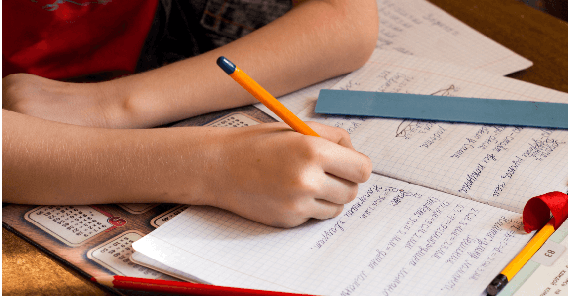 Kind oefent met omtrek naar oppervlakte berekenen in een schrift voor rekenen op de basisschool.
