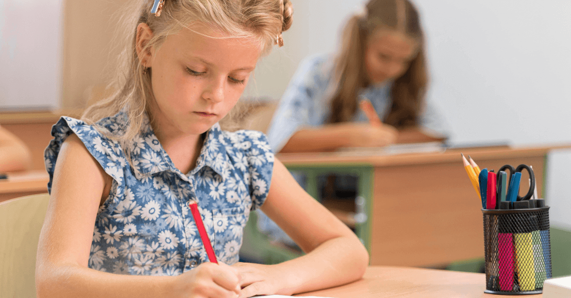 Kind oefent redactiesommen in de klas met potloden op tafel tijdens een rekenopdracht op de basisschool.