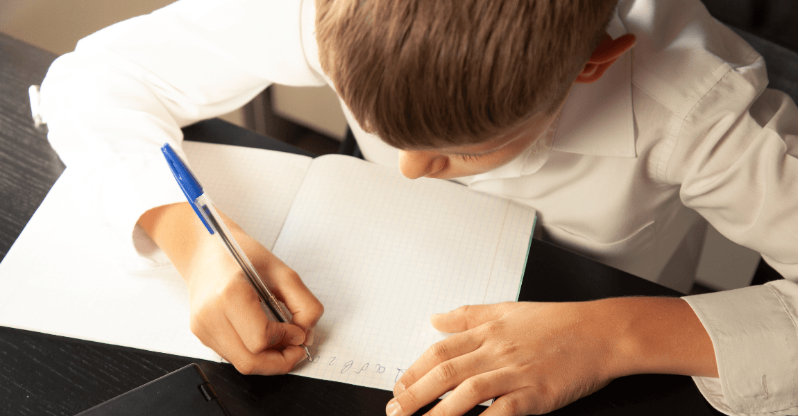 Kind oefent met schrijven aan elkaar in een schrift op school of thuis.