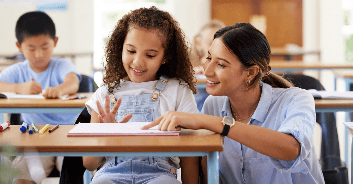 Leerkracht helpt basisschoolkind met begrijpend lezen en het oefenen van signaalwoorden in de klas.