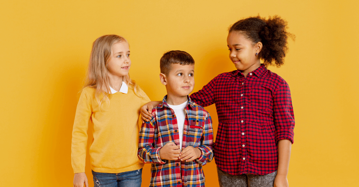 Drie basisschoolkinderen bij een gele achtergrond als beeld bij uitleg over voornaamwoorden oefenen en herkennen in zinnen.