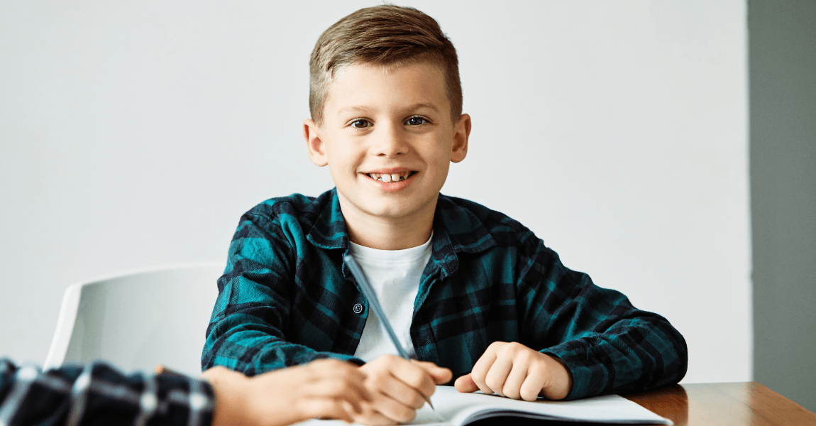 Kind oefent thuis met kolomsgewijs optellen en aftrekken aan tafel met een oefenboek.