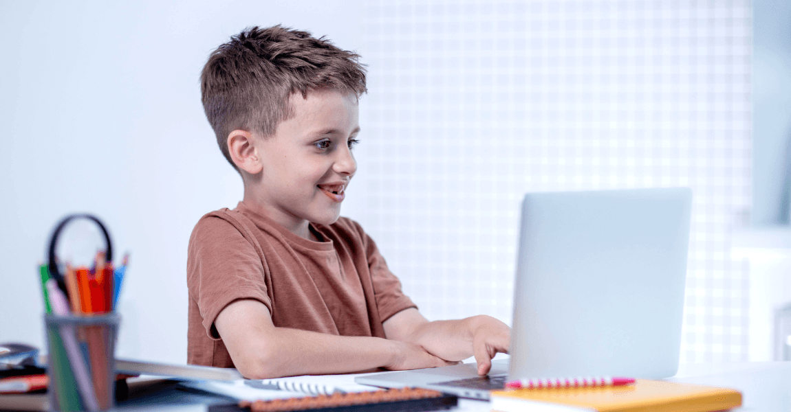 Kind oefent spelling met een spelletje op de laptop aan tafel.