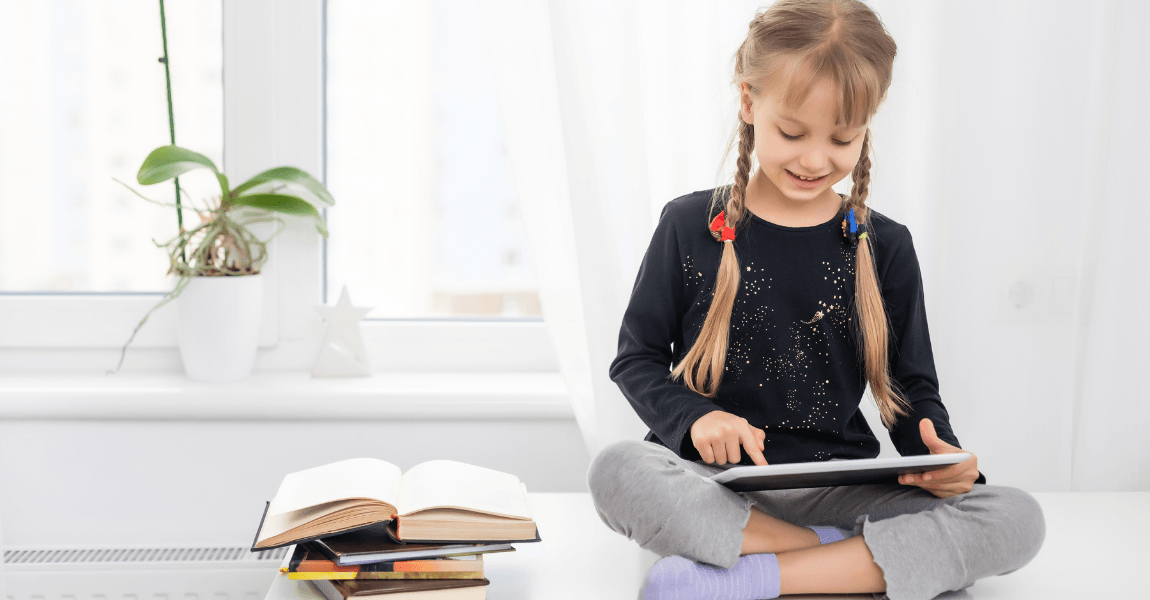 Kind oefent het voltooid deelwoord Engels op een tablet met boeken ernaast.
