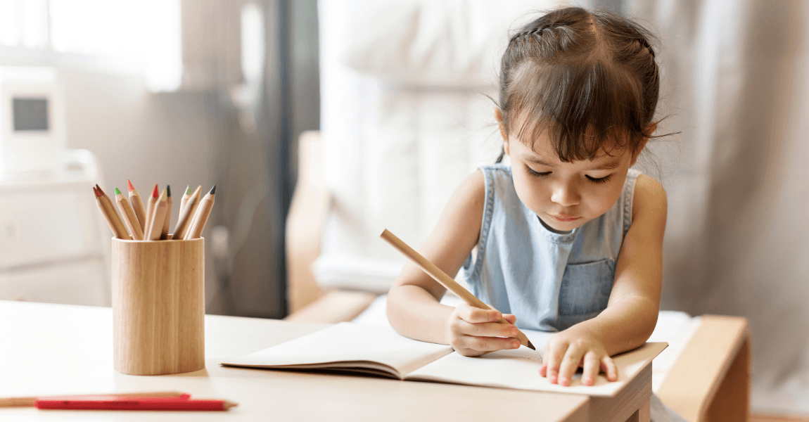 Kind uit groep 1 oefent voorbereidend schrijven met potlood en papier aan tafel.