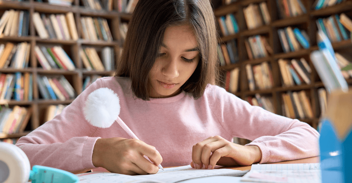 Meisje oefent spelling in de bibliotheek en leert woorden met koppelteken schrijven.