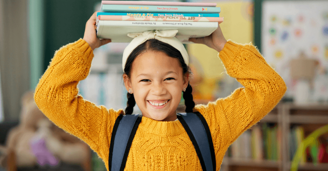 Vrolijk basisschoolkind met boeken om woorden met trema oefenen en spelling thuis leuker te maken.